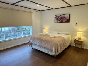 um quarto com uma cama grande e uma janela em La Plage - A Cosy Cottage in Phillip Island em Cowes