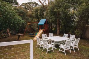 uma mesa e cadeiras num quintal com um parque infantil em La Plage - A Cosy Cottage in Phillip Island em Cowes