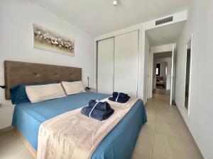 una camera da letto con un letto blu con asciugamani sopra di Flamenca Village apartment - close to the beach and La Zenia Boulevard a Orihuela Altre 22 foto