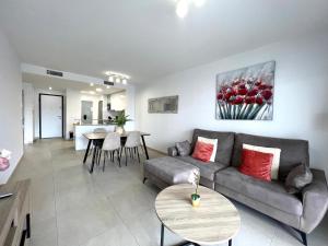 オリウエラにあるFlamenca Village apartment - close to the beach and La Zenia Boulevardのリビングルーム(ソファ、テーブル付)、キッチンが備わります。