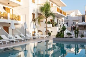uma imagem de uma piscina do hotel com cadeiras e guarda-sóis em Aristea Hotel em Rethymno Town