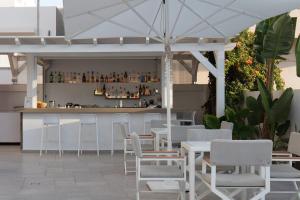 um restaurante com um bar com mesas e cadeiras brancas em Aristea Hotel em Rethymno Town