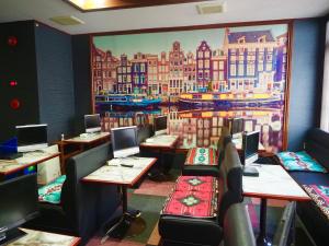 a restaurant with tables and chairs and a painting on the wall at Capsule Hotel Block Room in Tokyo