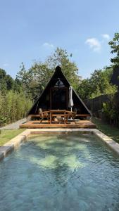 a hut with a table and a pool of water at Villa Verde the garden in Kejayan