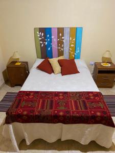 ein Bett mit einer roten Decke und zwei Nachttischen in der Unterkunft BYLELA in Tinogasta