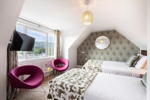 a bedroom with two beds and two purple chairs at Scotland's Spa Hotel in Pitlochry