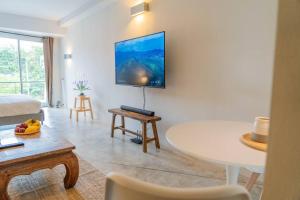 een woonkamer met een tafel en een tv aan de muur bij [NEW] Cozy Modern Studio with Pool & Gym in Koh Samui 