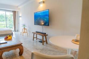 a living room with a table and a tv on the wall at [NEW] Cozy Modern Studio with Pool & Gym in Koh Samui 