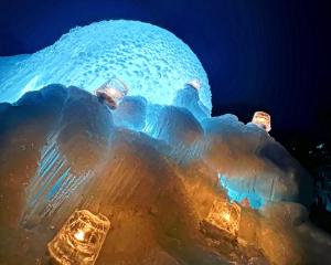 una estructura de hielo con luces encendidas por la noche en キャンパーズエリア恵庭 TCS Village, en Eniwa