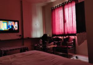 um quarto com uma cama e uma televisão num quarto em Hotel Udayshree Palace Latur em Lātūr