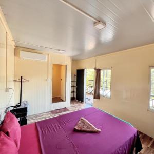 um quarto com uma cama com um cobertor roxo em CornerStone Nesat in Nesat Village em Phumĭ Chroŭy Svay