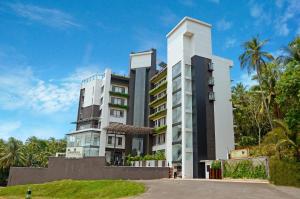 a tall white building with palm trees in the background at Copper Folia in Kozhikode