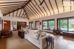 a living room with a white couch and windows at Wander Beyond by StayVista - Featuring a Bali-themed abode and a refreshing swimming pool in Alibaug