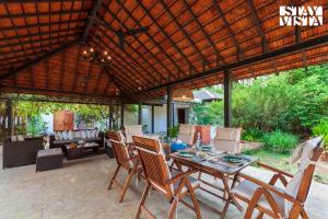 an outdoor patio with a table and chairs at Wander Beyond by StayVista - Featuring a Bali-themed abode and a refreshing swimming pool in Alibaug