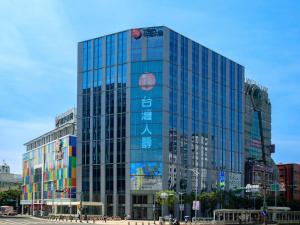 un edificio de cristal alto con un cartel. en Sotetsu Grand Fresa Taipei Ximen en Taipéi