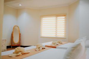 a bedroom with two beds and a mirror and a window at RNJ Hotel in Baguio