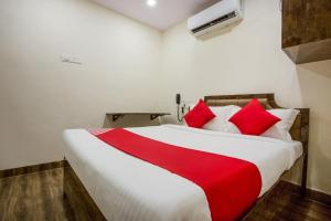 a bedroom with a large bed with red pillows at OYO Flagship Hotel Subodaya in Nerul