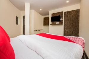 a red and white bed in a room with a tv at OYO Flagship Hotel Subodaya in Nerul