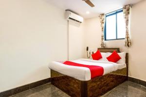 a bedroom with a bed with red pillows at OYO Flagship Hotel Subodaya in Nerul