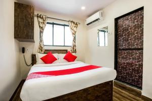 a bedroom with a large bed with red pillows at OYO Flagship Hotel Subodaya in Nerul