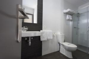 a white bathroom with a toilet and a sink at Hostal Emeritae in Mérida