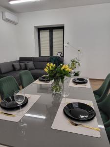 uma mesa de jantar com pratos pretos e flores amarelas em Luksusowy Apartament Sucumin 95mkw 