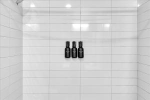 três garrafas de vinho penduradas numa parede de azulejos brancos em Near Hwykingpoolfitnessyoga Studiogame Room em Rogers