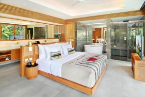 a bedroom with a large bed and a bathroom at Kaamala Resort Ubud by Ini Vie Hospitality in Ubud