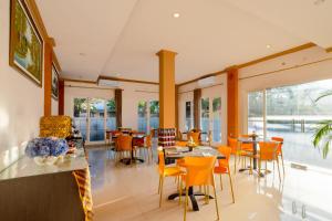 un restaurante con mesas, sillas y ventanas en The Kanjeng Hotel Kuta en Kuta