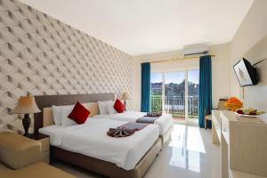 a hotel room with two beds and a window at The Kanjeng Hotel Kuta in Kuta