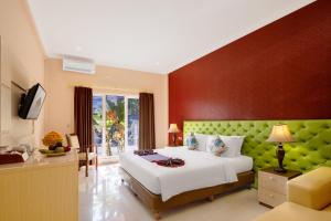 um quarto com uma cama grande e uma cabeceira verde em The Kanjeng Hotel Kuta em Kuta