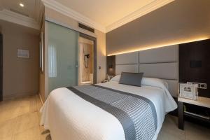 a bedroom with a large white bed and a desk at Habitus Hotel Europa in Pamplona +44 photos