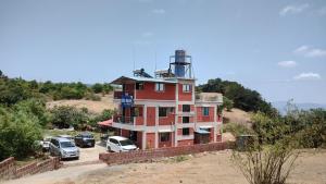 a red building with cars parked in front of it at ELITE HOME in Mahabaleshwar