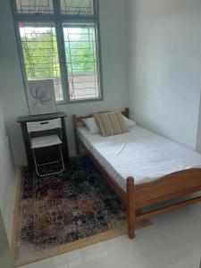 a bedroom with a bed and a desk with a laptop at Homestay Merbau Changloon in Changlun