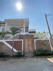 a brick house with a door and a palm tree at Emka Villa Traditional Minimalist in Malang
