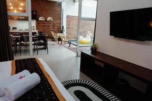 a living room with a bed and a tv and a dining room at Emka Family Villa Malang in Malang
