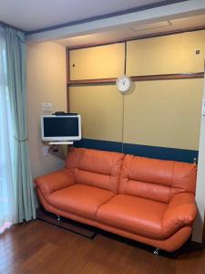 a couch in a living room with a tv and amonitor at KYARA Hotel 白鳥 in Tokyo
