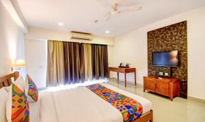 a bedroom with a bed and a television and a desk at FabHotel Prime Indeedcare Hotel & Resorts in Jojera