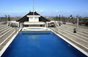 a pool on the roof of a building with a gazebo at Bali Paradise City Hotel in Denpasar