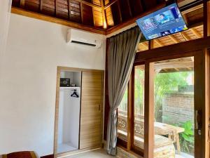 een kamer met een koelkast en een televisie aan het plafond bij Sridewi Villas Ubud in Ubud