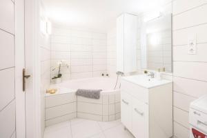 La salle de bains blanche est pourvue d'une baignoire et d'un lavabo. dans l'établissement Deluxe & Cozy Dream Home in the Heart of Budapest, à Budapest