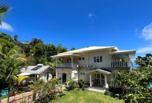 a large white house with a yard at Royal Bay Apartment in Anse Royale