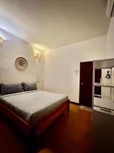 1 dormitorio con 1 cama y reloj en la pared en Tiga Dara Homestay, en Gili Trawangan