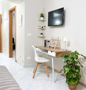 a desk with a chair and a tv on a wall at La casa di Angela in Monreale