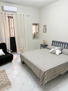 um quarto branco com uma cama e uma cadeira em La casa di Angela em Monreale