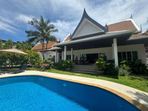 a villa with a swimming pool in front of a house at Montaplan Villa by G Estate in Rawai Beach