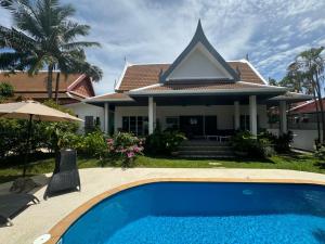 a house with a swimming pool in front of a house at Montaplan Villa by G Estate in Rawai Beach