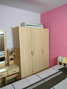 Zimmer mit einem Schrank, einem Schreibtisch und einer rosa Wand in der Unterkunft Lexus in Ahmedabad