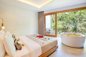 1 dormitorio con bañera y ventana grande en Kaamala Resort Ubud by Ini Vie Hospitality en Ubud