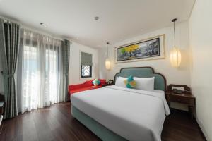 a bedroom with a large white bed and windows at Hanoi Calista Hotel in Hanoi